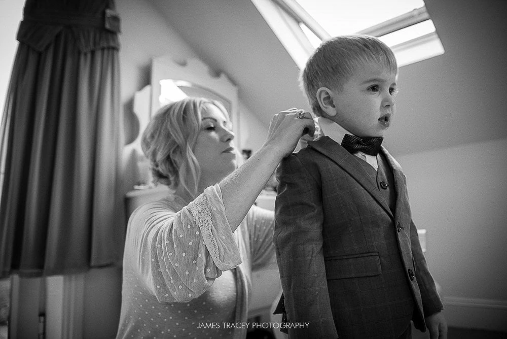 young boy having his wedding suit put on