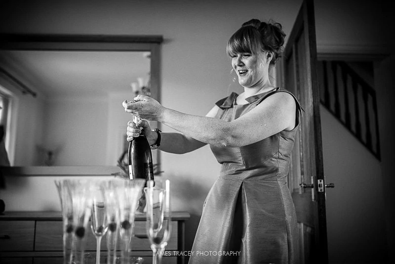 bridesmaid opening a bottle of moet champagne before a wedding at the plough inn in hathersage