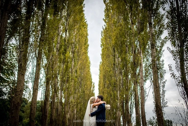 bride and groom stood in front of tall trees