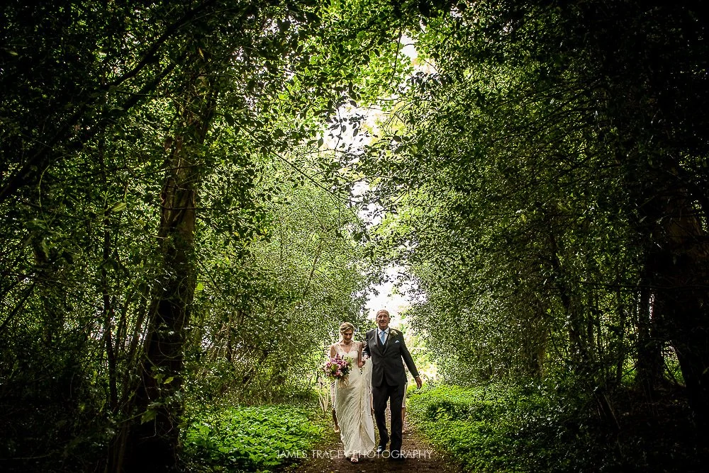 bride walking down aisle under trees