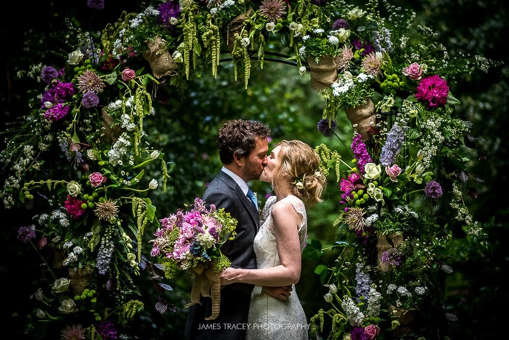 bride and groom kissing under arch