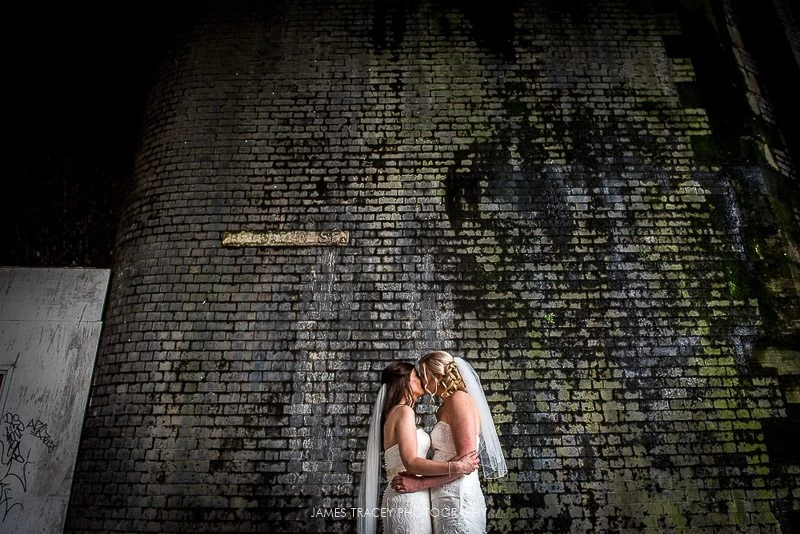 two brides kissing in front of wall