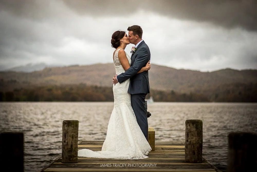 bride and groom kissing on lake windermere