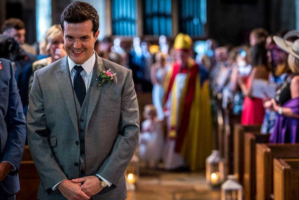 smiling groom at top of wedding aisle