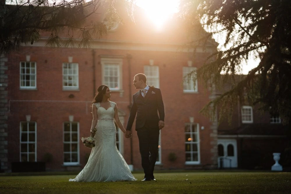 bride and groom walking at sunset at mottram hall