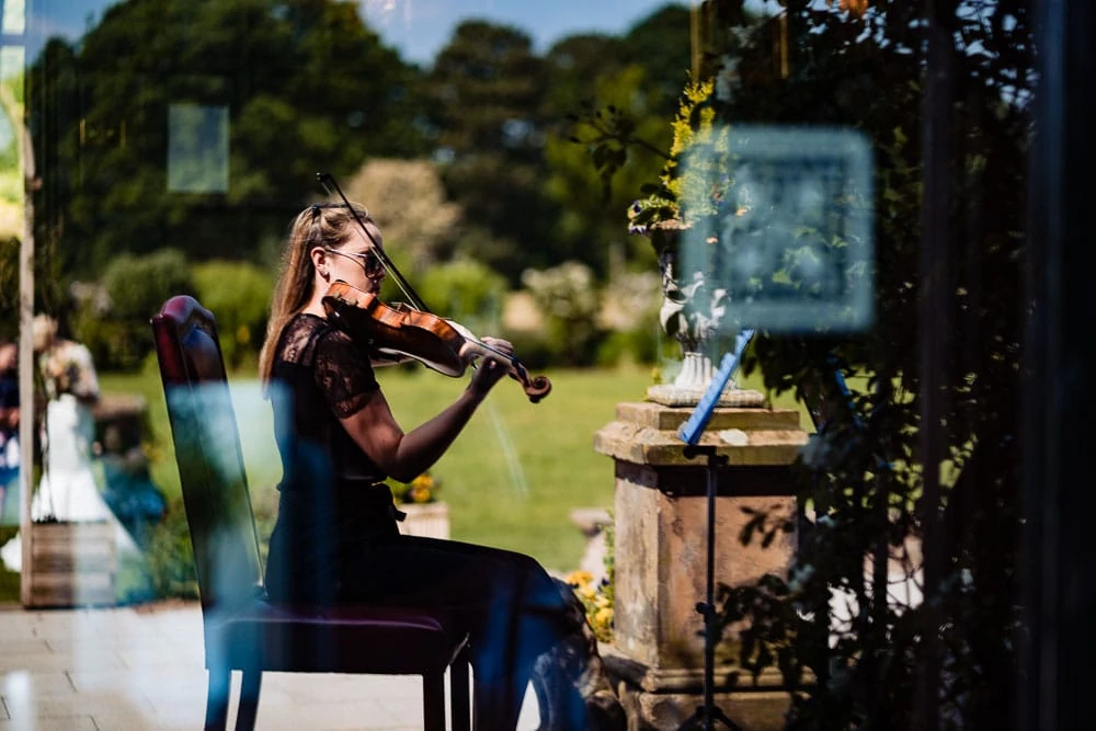 violinist reflected in window