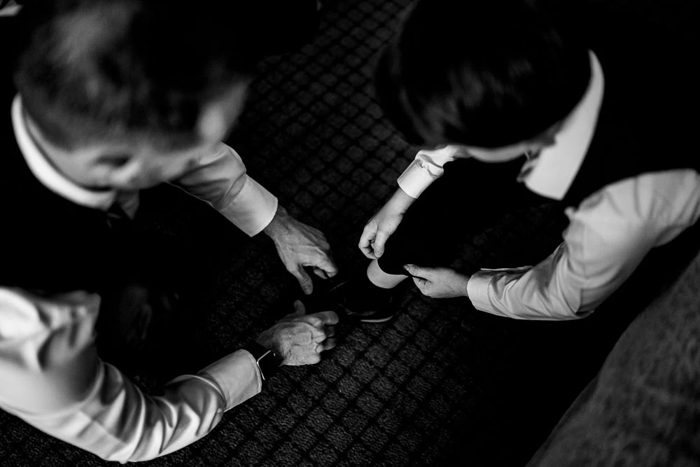 groom and his son lacing up shoes