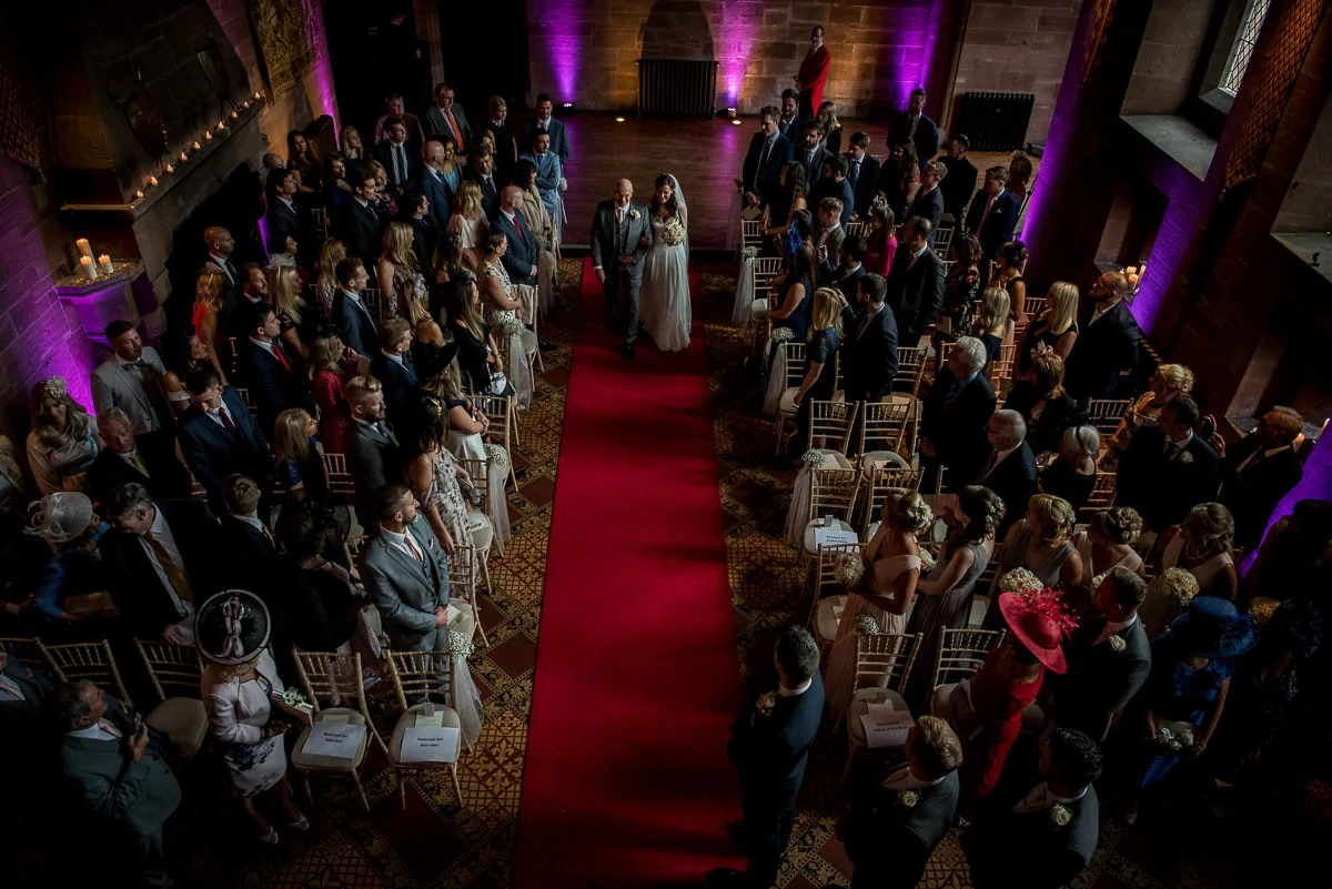 dramatic photo of bride walking up the ailse at peckforton castle wedding