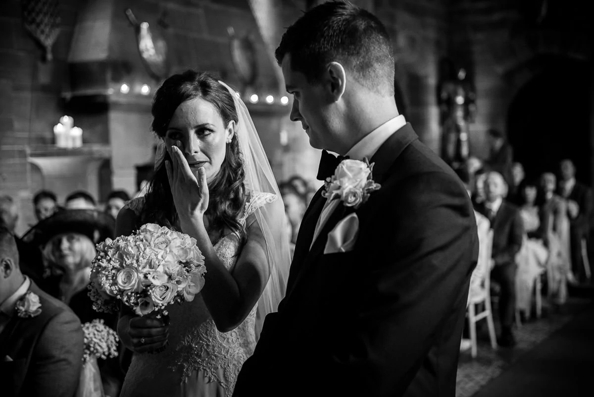bride wiping tear from her eye at peckforton castle