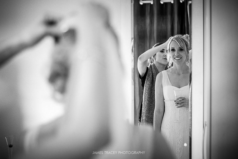 bride putting her veil on reflected in a mirror before wedding at plough inn at hathersage