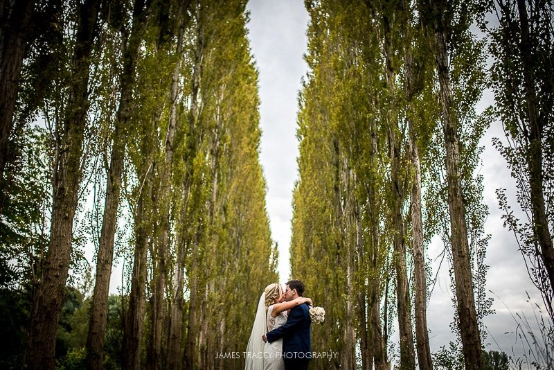 bride and groom stood in front of tall trees