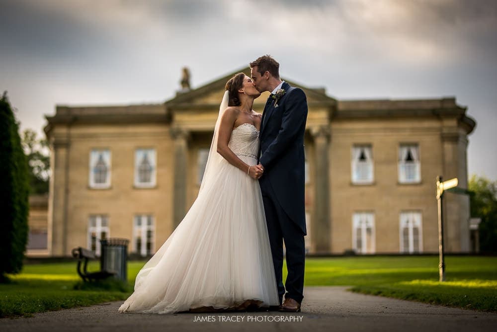 bride and groom kissing in front of the mansion