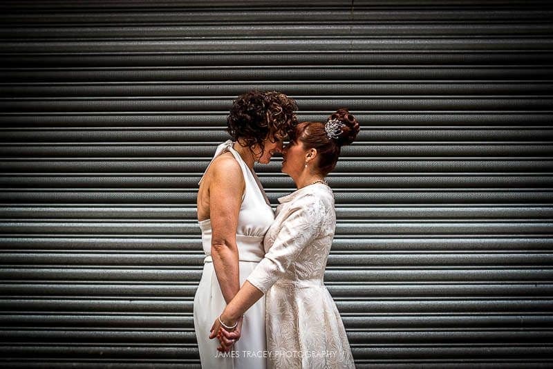 brides kissing in front of a shutter