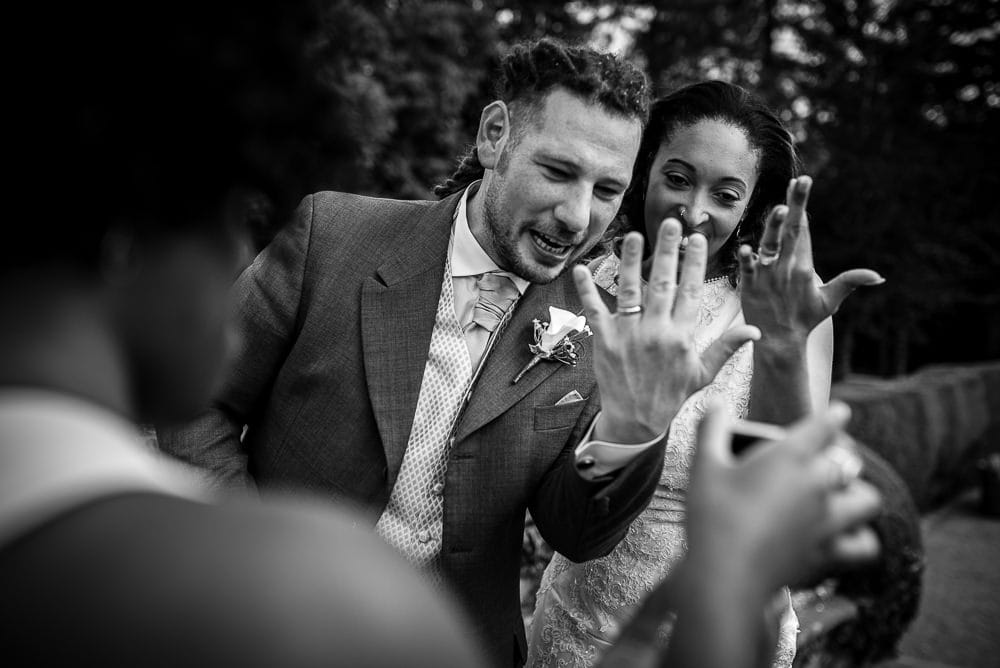 bride and groom showing off rings