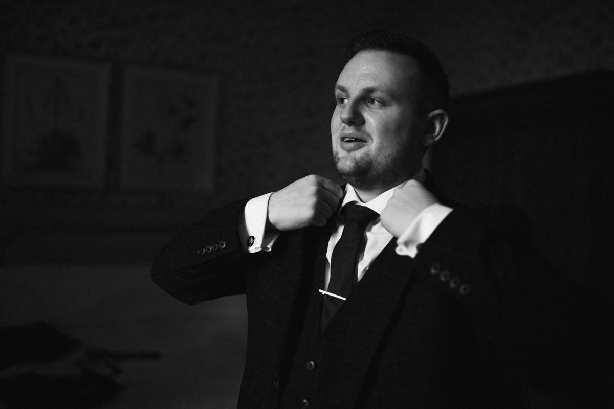 groom putting his suit jacket on