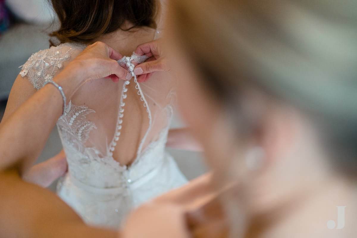 bride being buttoned into her wedding dress