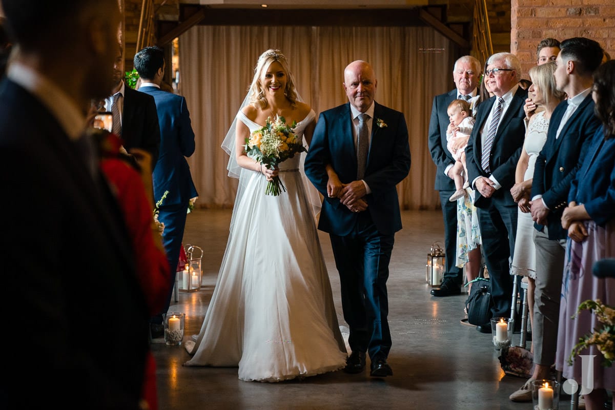 bride walking up the aisle at the holford estate